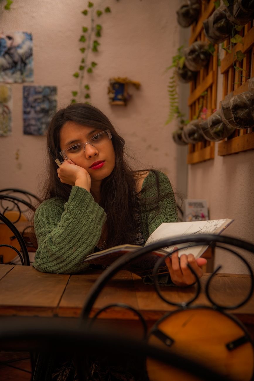 Young woman writing in a cozy café with warm lighting.